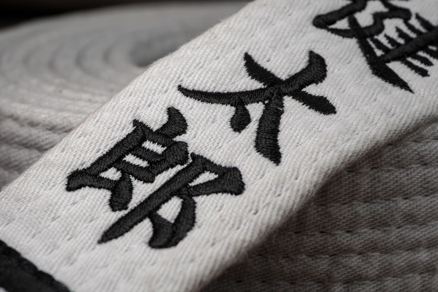白い帯に黒糸で施した日本語の名前刺繍の接写