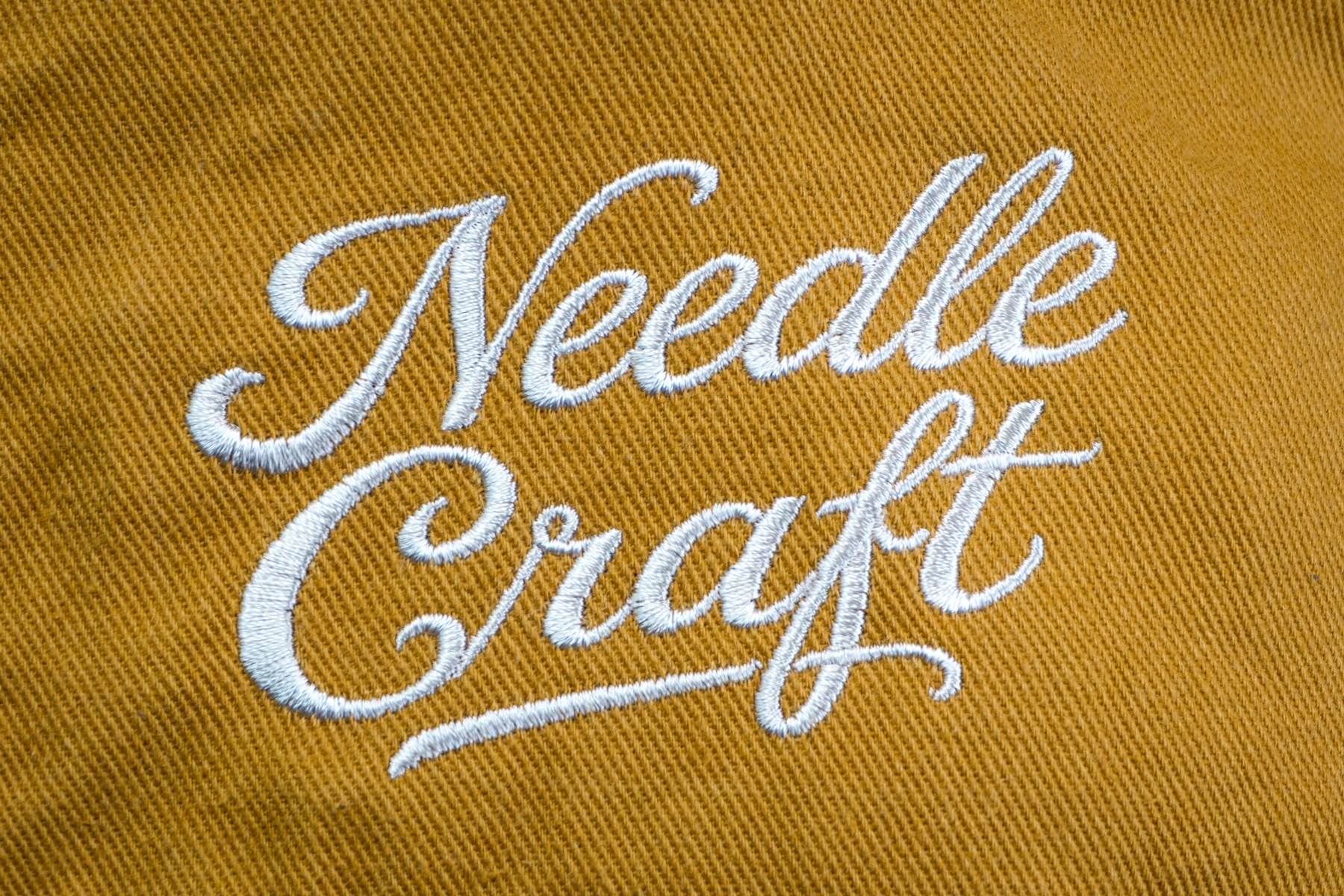 マスタード色の生地に白い糸で施したNeedle Craftの刺繍